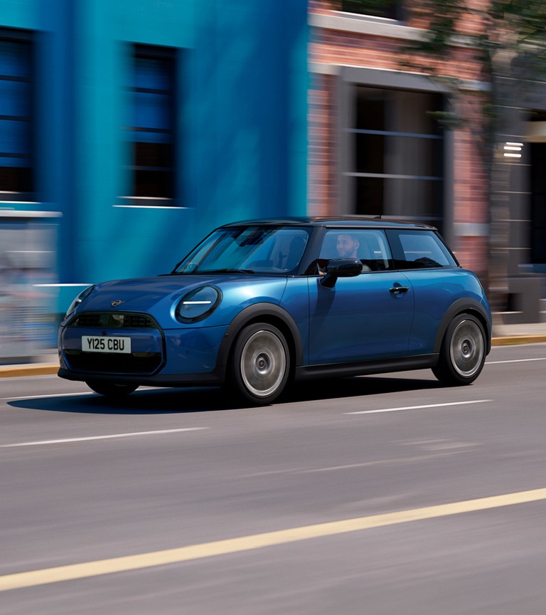 MINI Cooper speeds along a sunny street, with colourful buildings in the background, showcasing urban life.